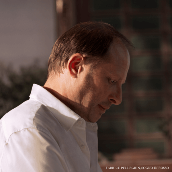 A man in profile, wearing a white shirt, appears deep in thought against a softly lit background.