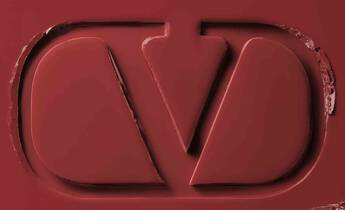 A close-up of a deep red surface featuring an embossed logo with a stylized design.